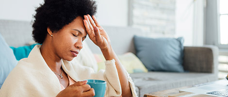 A woman feeling her forehead and experiencing Coronavirus symptoms.