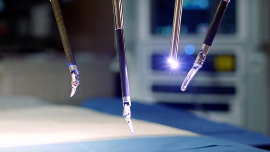 Robotic surgery tools hanging down from the machine and hovering over the surgery table by a couple of inches.