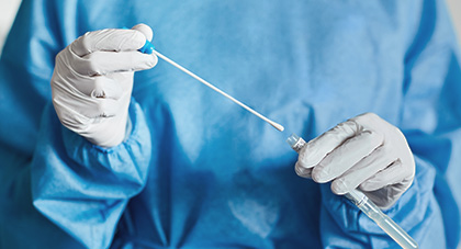 A nurse in PPE, prepping a covid test swab.