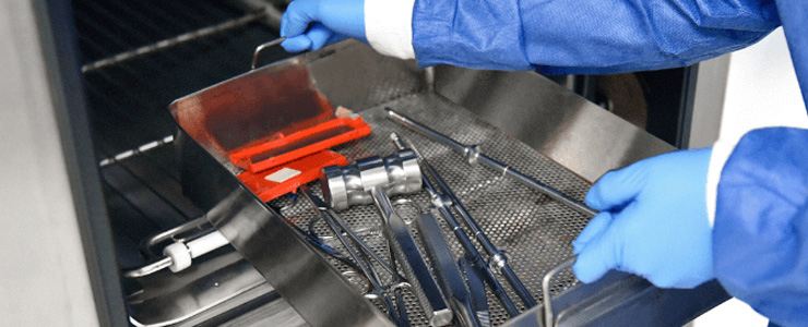 A lab technician placing medical instruments in the washer.