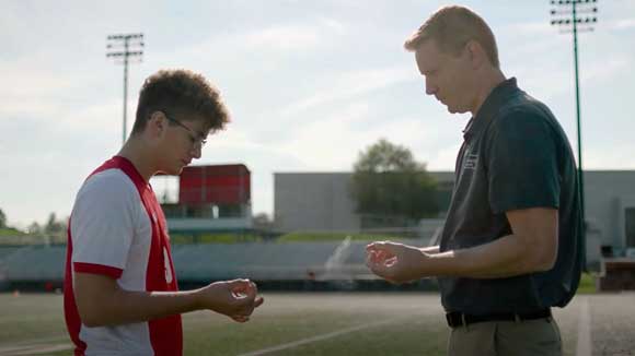 A sports medicine fellow examines an athlete on the sidelines.