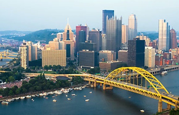 A female clinician examines cells in a petrie dish under a microscope.