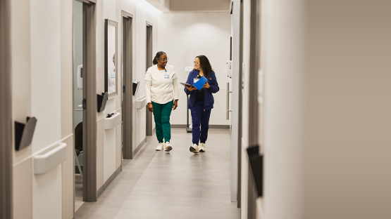 Two female healthcare providers walking down a hospital hallway