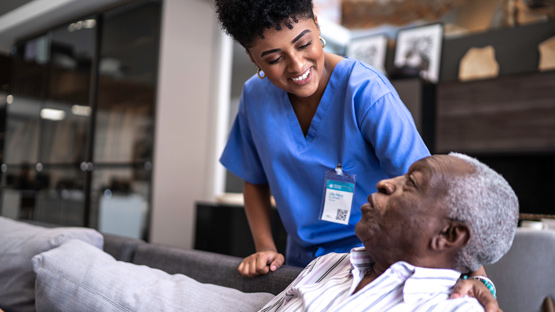 A nurse smiling and conversing with an elderly male patient.