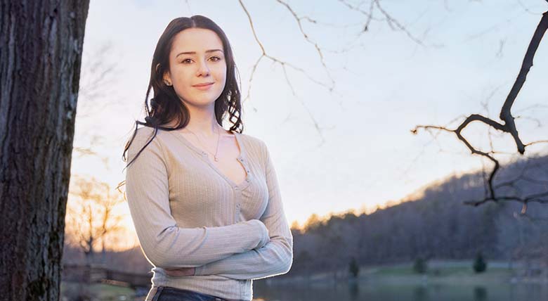 AHN patient Rachel Wilson having her photo taken standing at the side of a body of water next to a tree.