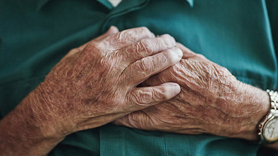 An old man holding his hands on his chest.