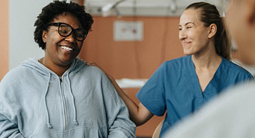 An AHN health care professional laying her hand on a patients shoulder.