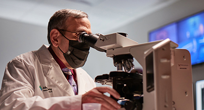 Cancer researcher looking through a microscope