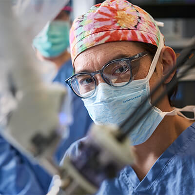 Surgeon in glasses, cap, mask, focused on operation. 