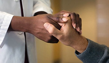 A doctor's hands holding a patient's hand