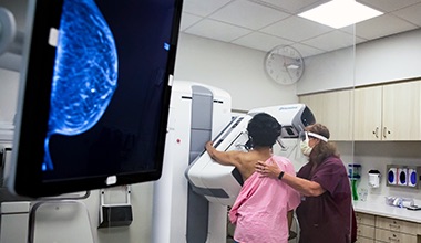 A monitor showing the scan as a nurse helps a patient getting a mamogram 