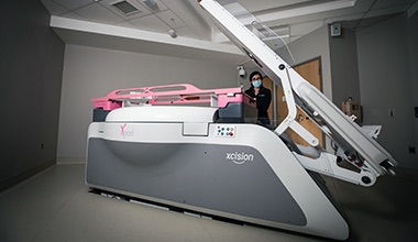 A medical professional watches a patient in a room with high tech cancer equipment