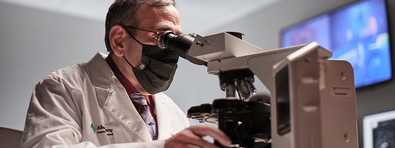 A medical professional in a lab coat looking in a microsope