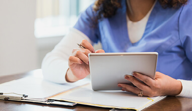 Close up of an AHN nurses hands holding a digital tablet and checking a patient's file