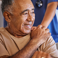 AHN patient touching the hand of AHN Cancer Navigation team member that is resting on his shoulder 