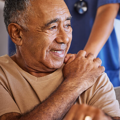 AHN patient touching the hand of AHN Cancer Navigation team member that is resting on his shoulder 