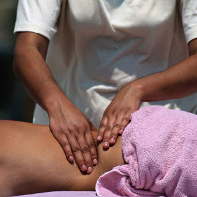 A closeup view of a massage therapist massaging their patient's lower back.