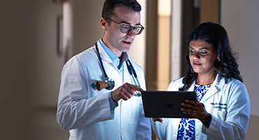 Two AHN cardiovascular doctors reviewing a medical chart on a digital tablet