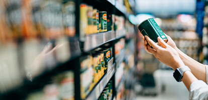 Hands holding a can of vegetables pulled from a shelf of canned goods at a Healthy Food Center