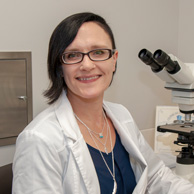 laboratory research associate smiling next to microscope