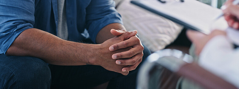 Close-up of a patient with hands clasped during a pain management consultation.