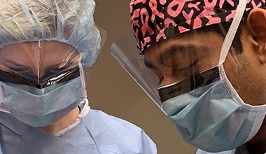 Medical professionals wearing protective equipment during surgery looking down in an operating room 