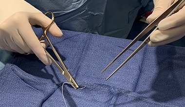 A close up view of a doctor's gloved hands holding surgical equipment