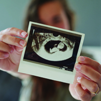 A woman holding up a sonogram image of her baby