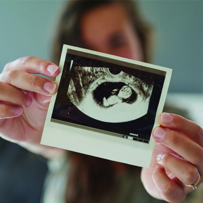 A woman holding up a sonogram image of her baby