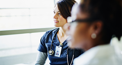 Female medical professional in scrubs with female patient 