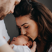 image of a woman kissing her baby's forehead